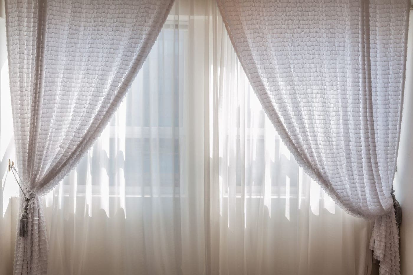 Voilages clairs devant une fenêtre, à déposer et laver